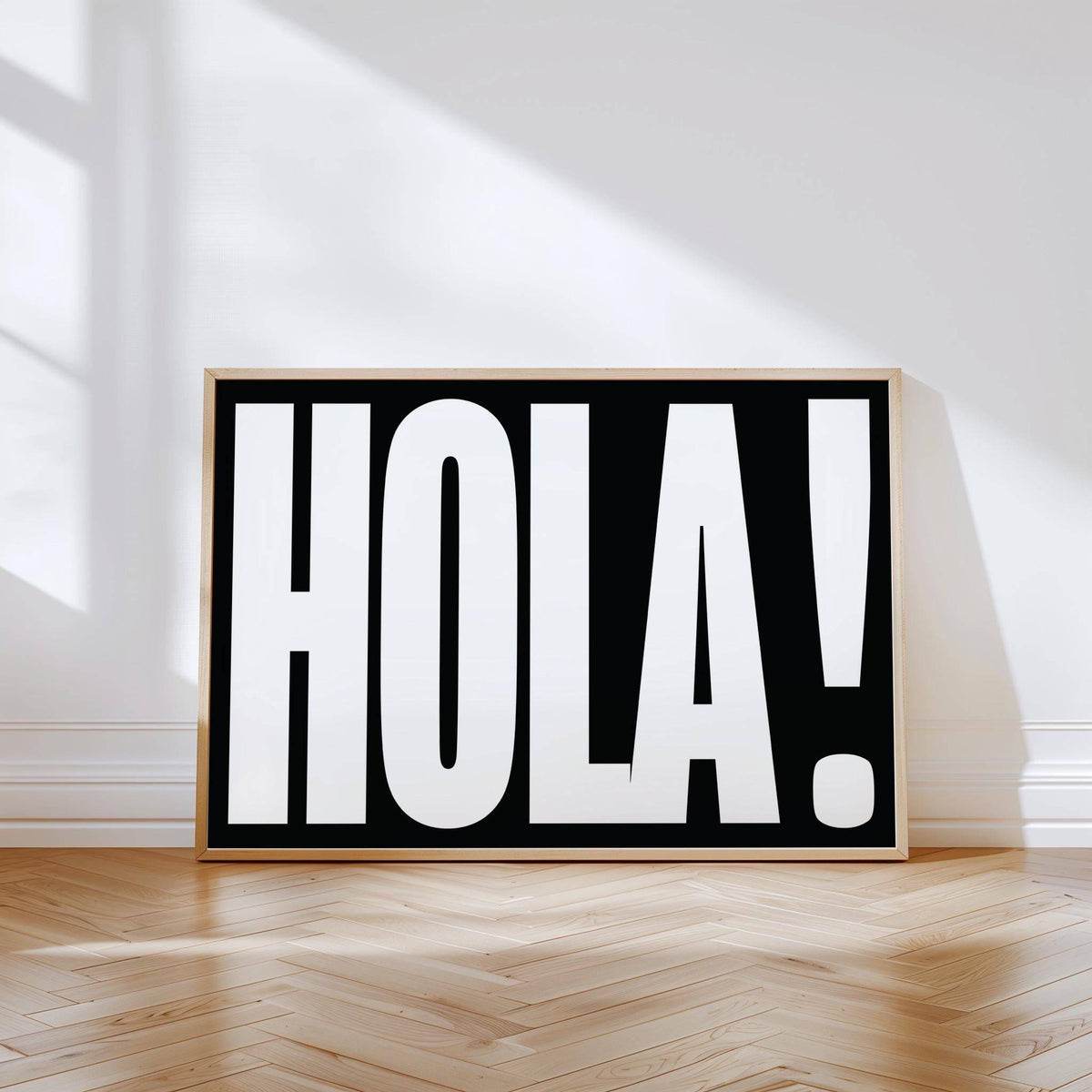 Posters with Typography leaning black and white HOLA text print on a wooden floor with sunlight