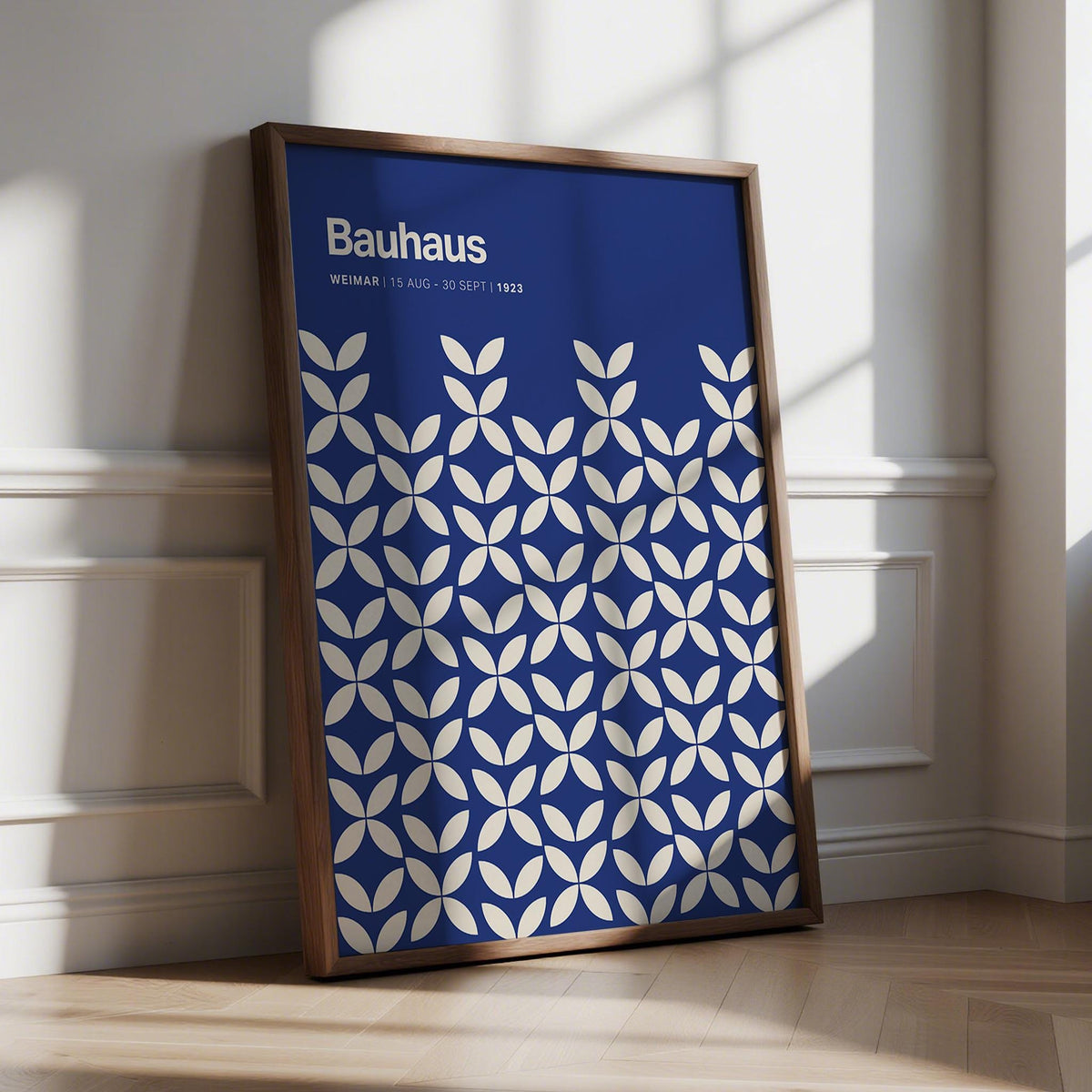 Framed print close-up of blue modern wall art with white petal shapes leaning against a cream wall