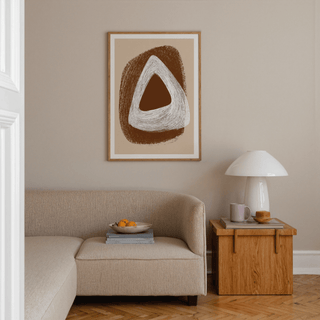 Boho Geometric Art Print above a beige sofa with abstract brown and white triangle shapes and a wooden side table