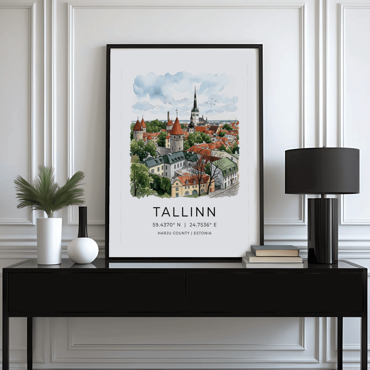 Tallinn City wall art illustration with watercolour style atop a black sideboard with books and a lamp