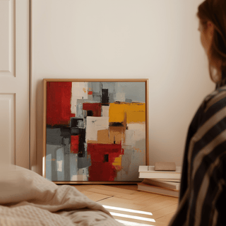 Colorful Abstract Poster Art leaning on floor with books beside it in a softly lit room
