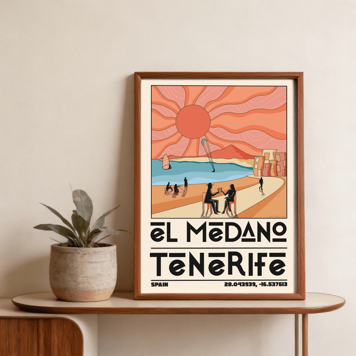 Framed Tenerife Travel Poster with stylised beach scene and large orange sun on table with plant