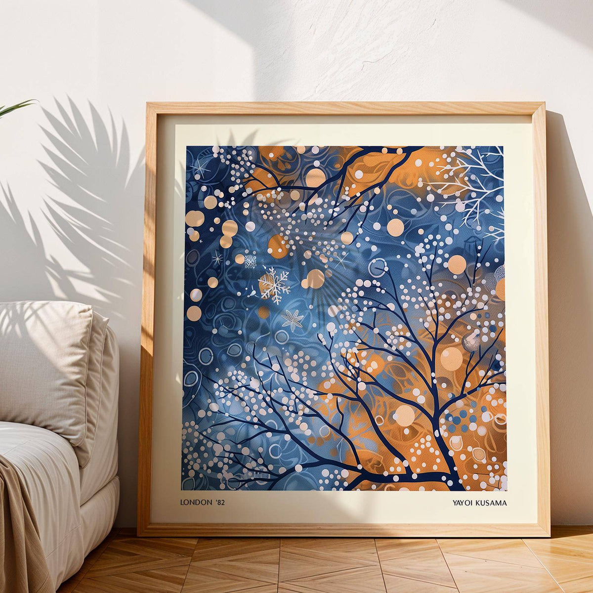 Framed Winter Scene wall art with blue and orange abstract branches leaning by a beige sofa