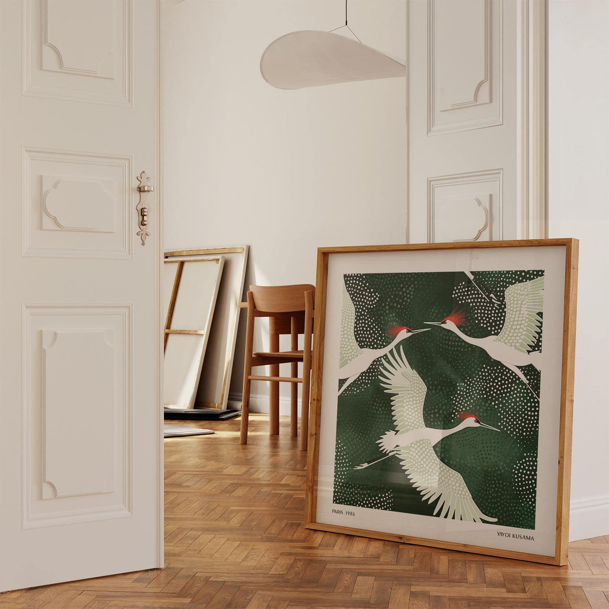 White Crane Birds Art print leaning on wooden parquet floor with chair and mirror behind