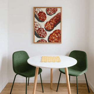 Print on a wall in a dining nook showing an illustration of sliced salami in red and brown tones above a white round table with green chairs