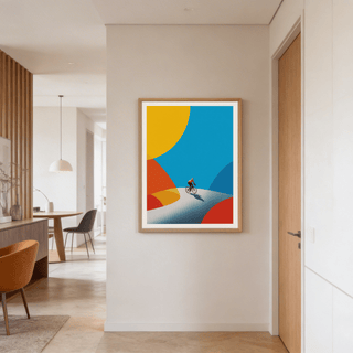 Cycling Art Print in natural wood frame on a cream wall above an orange chair in a modern room