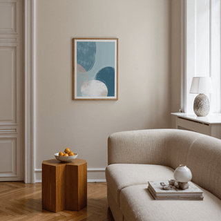 Abstract blue art print featuring large blue and white circles above a wooden side table in a beige living room