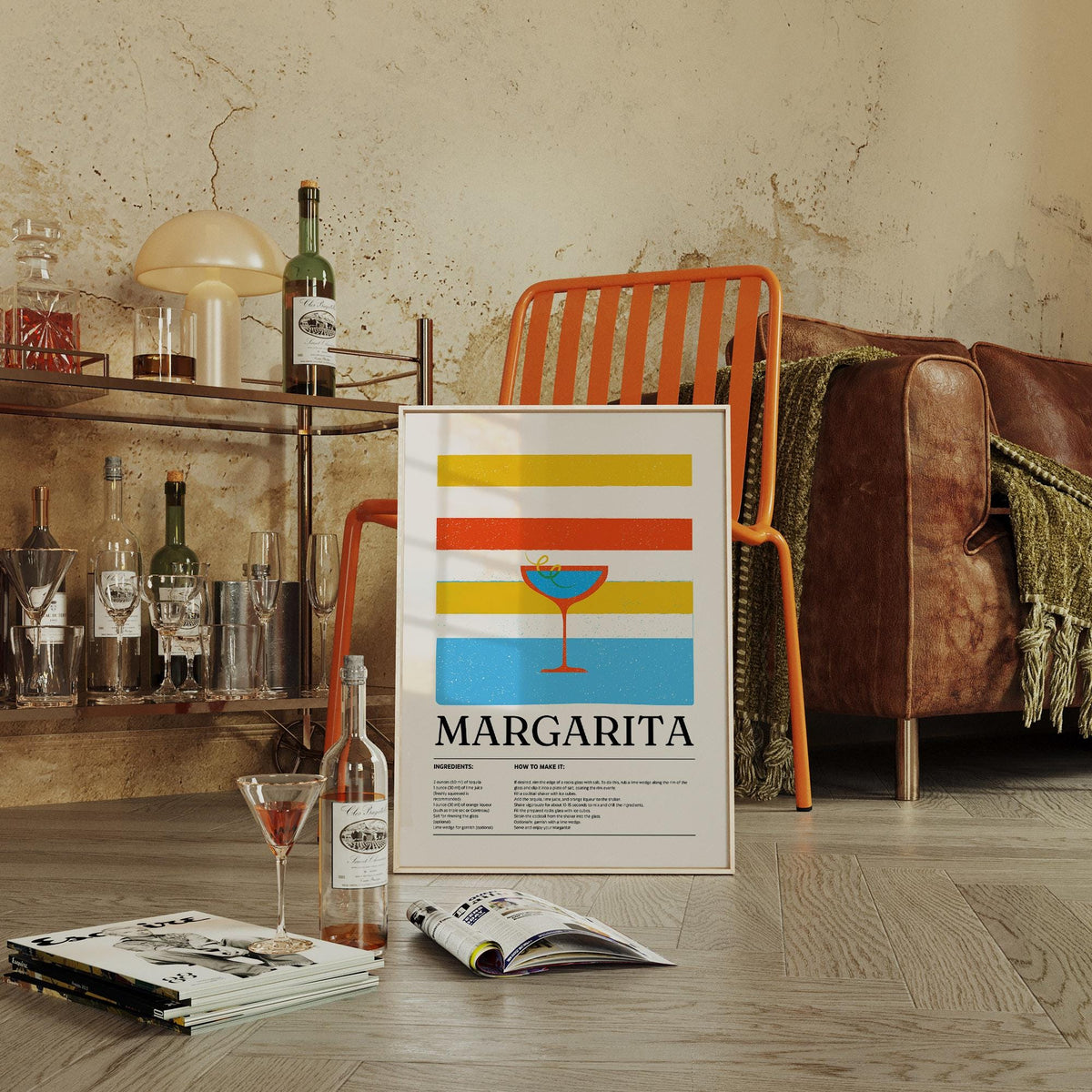 Margarita wall art print leaning on floor by an orange chair with a cocktail glass nearby