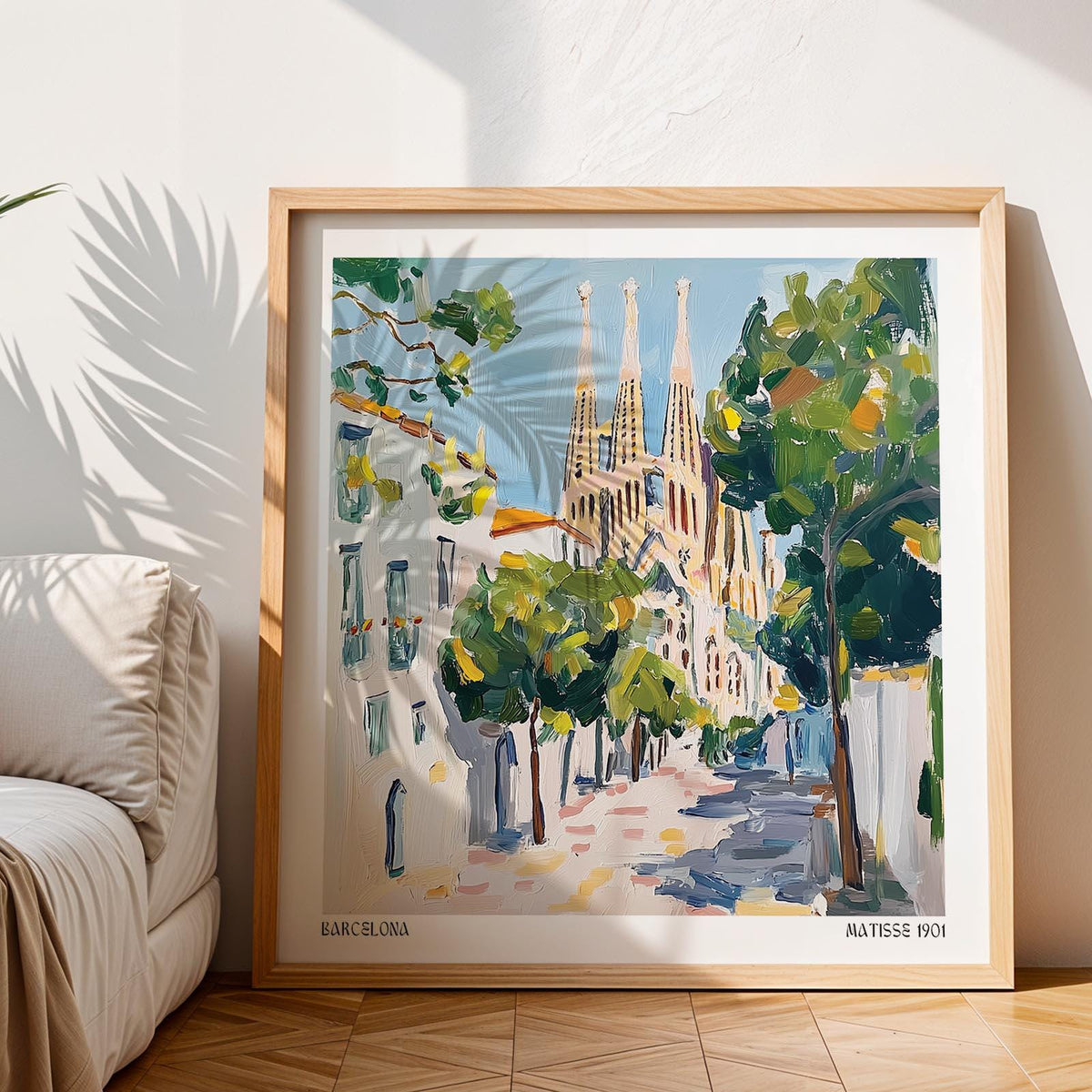 Framed Barcelona Boulevard Poster showing Sagrada Familia with green trees leaning on floor beside sofa