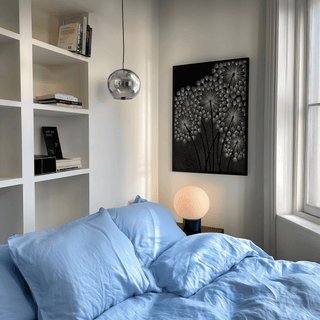 Dandelions wall art of white dandelion seed heads in a minimalist style above a bedside lamp