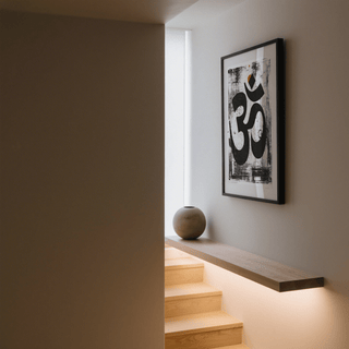 Abstract Om Art Print print on a wall in a stairwell with a wooden floating shelf and round ceramic vase