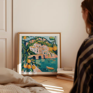 Amalfi Coast painting leaning on floor with books beside in a softly lit room
