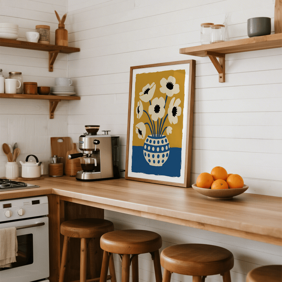 Flower art print leaning on a kitchen counter next to an espresso machine and bowl of oranges