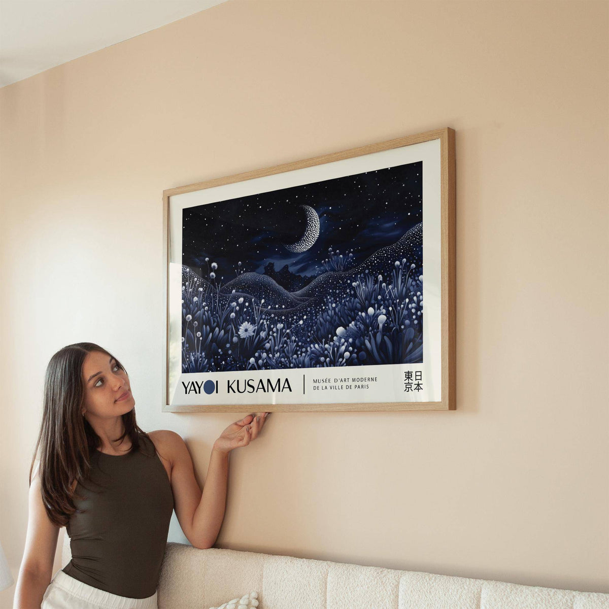 Night Art framed print of a crescent moon over floral hills in blues beside a woman on a sofa