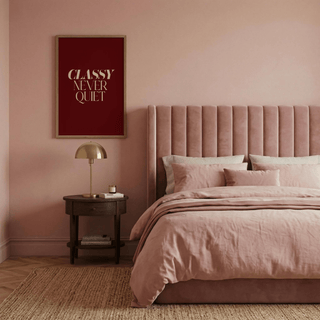 Classy wall art with beige text on burgundy above a side table and lamp in a bedroom