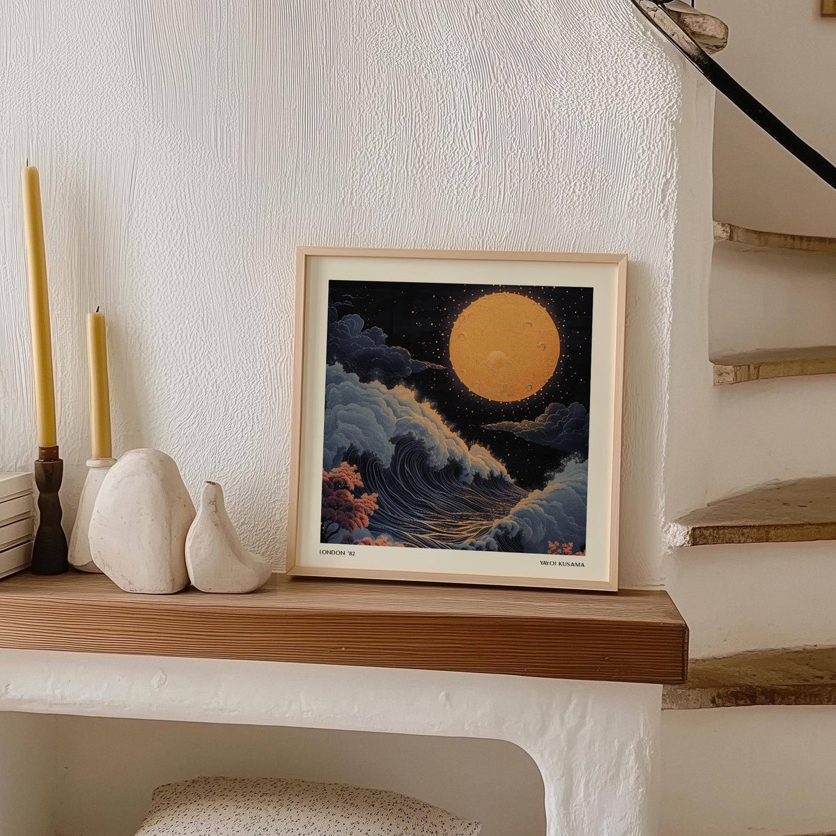 Print leaning on a shelf showing Japanese art pictures with a large orange moon and blue waves next to candle holders