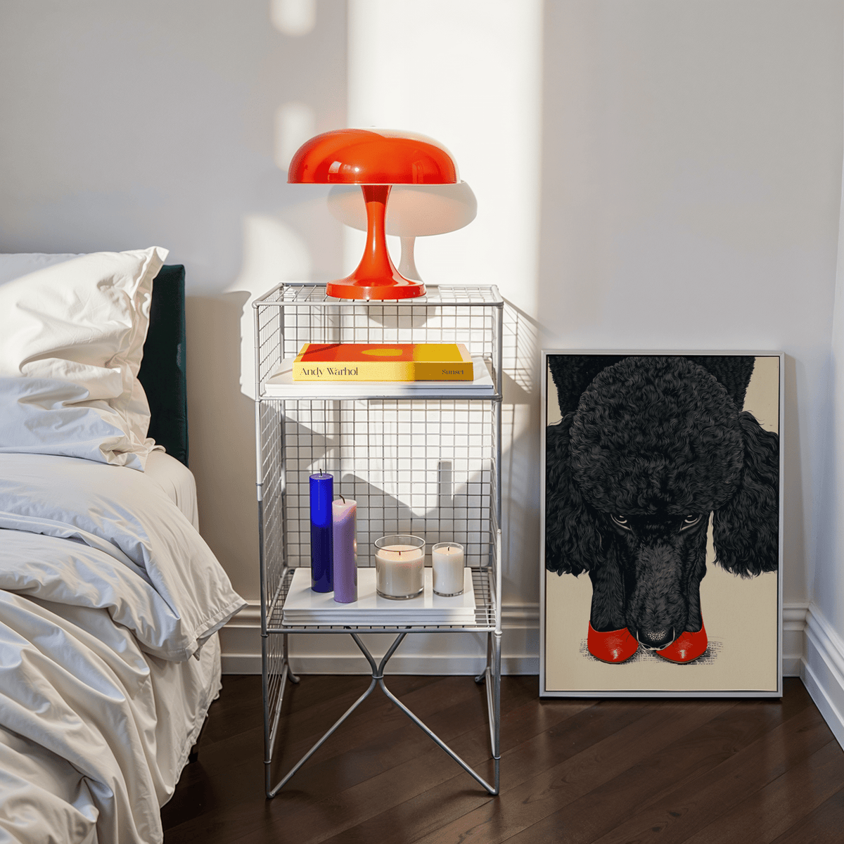 Poodle wall art leaning on floor showing a black poodle with red shoes beside a bedside table and orange lamp