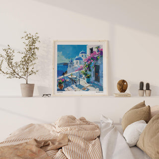 Santorini wall art prints in watercolour style above a beige striped throw on a bed