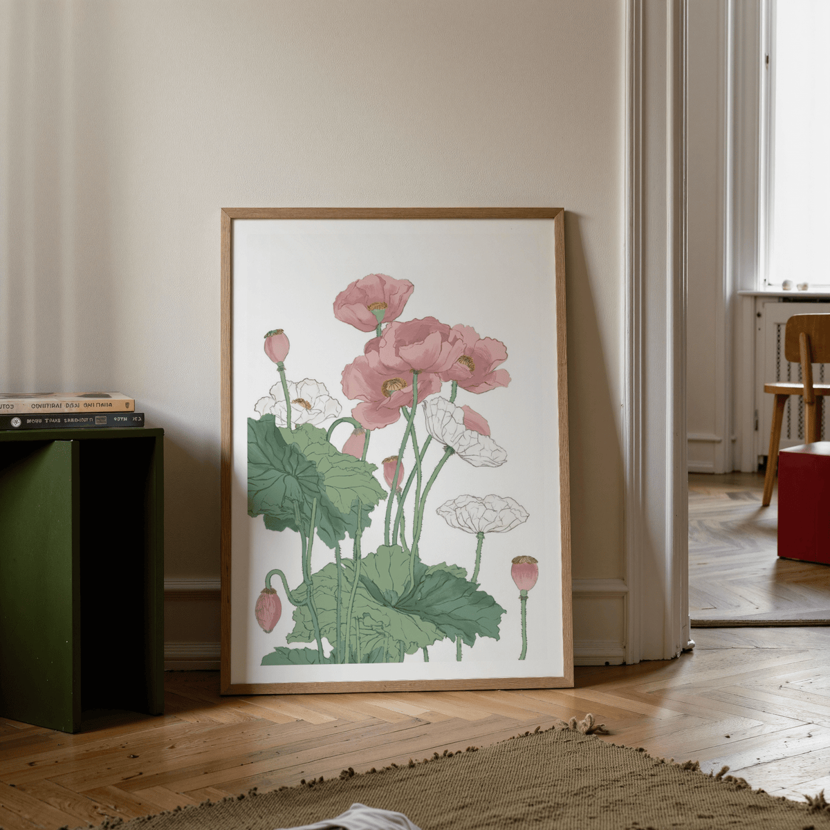Botanical flower print leaning on a wooden floor with a stack of books nearby