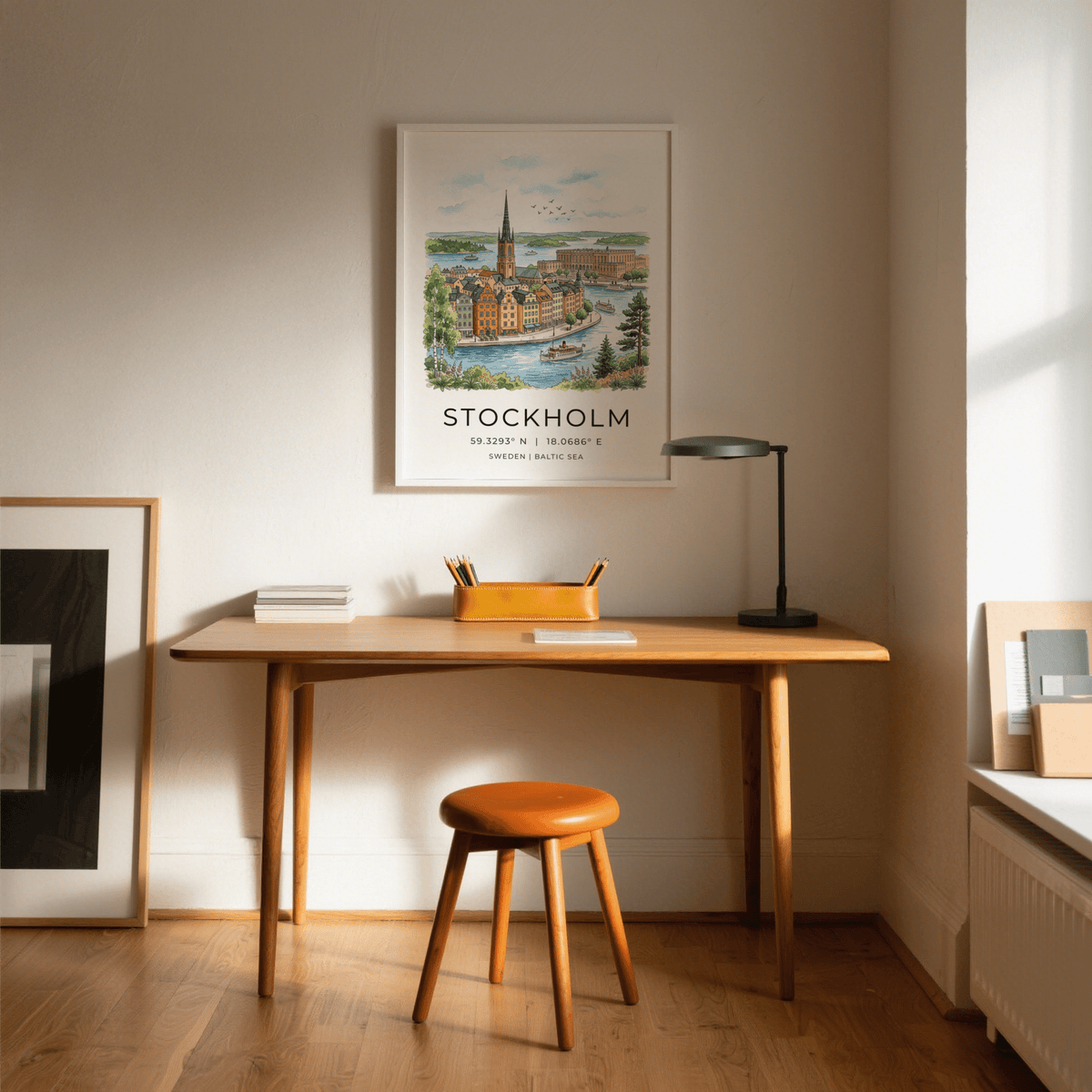 Stockholm City Art Print on wall above a wooden desk with a lamp and stool in a bright room