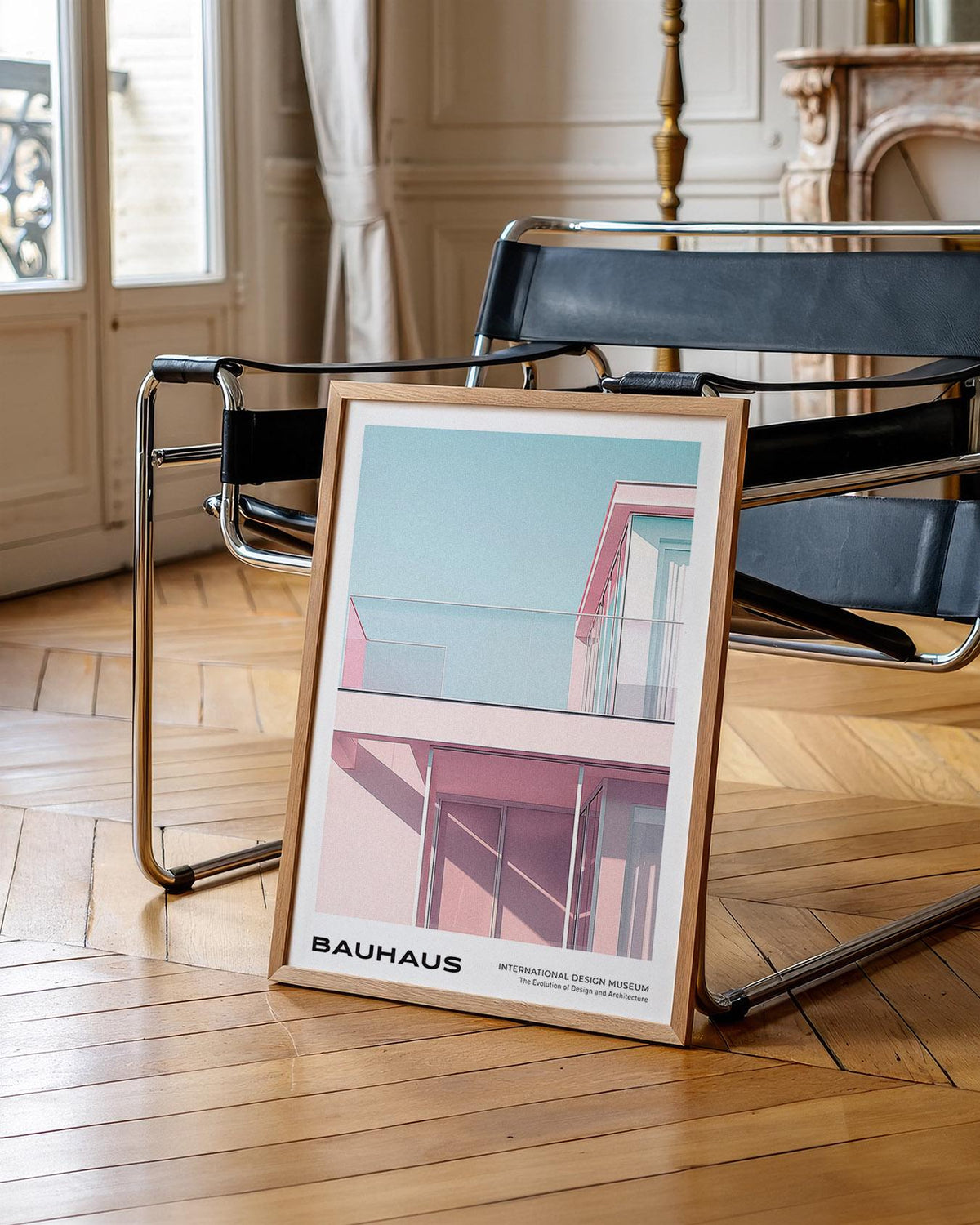 Print leaning on floor showing Bauhaus style building facade in pink and blue by a black modern chair