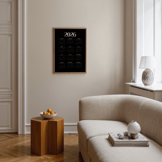 Modern Calendar Print on wall with minimalist black and white design above orange bowl on wooden side table in living room