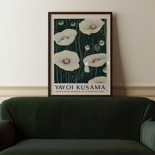 Poppy wall art with white poppy flowers on a dark green background above a green leather sofa