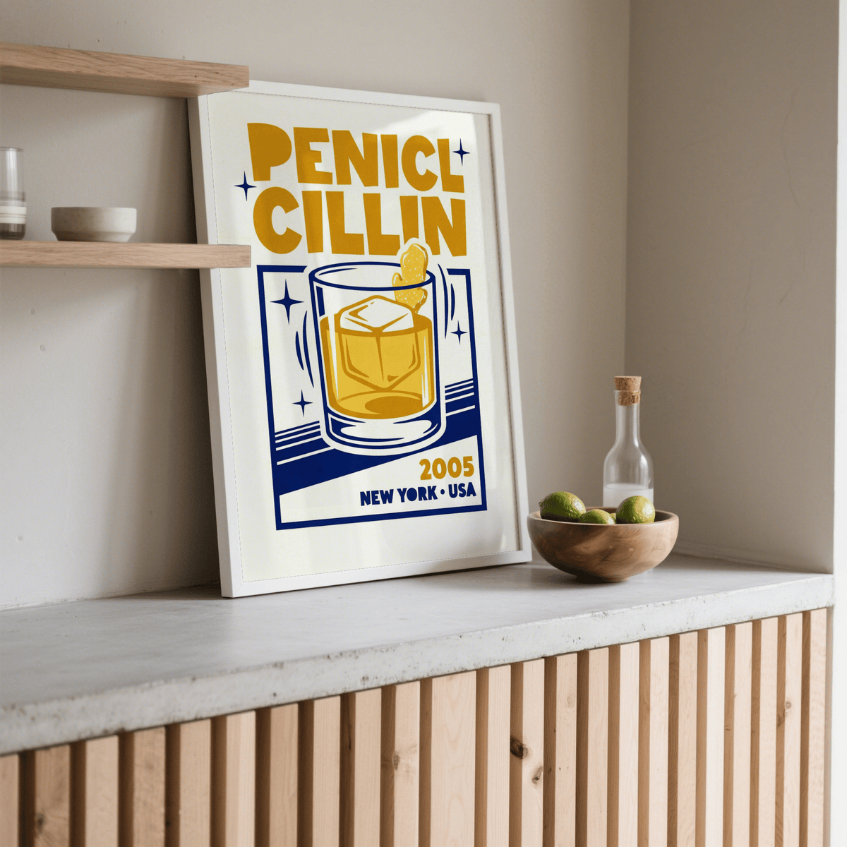 Print leaning on a wooden surface with a bowl of limes and bottle nearby