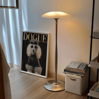 Print leaning on a floor by a lamp and stack of books featuring a poodle in a leather jacket