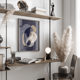 Print on a wall in a bright workspace featuring abstract organic shapes in beige and grey near pampas grass