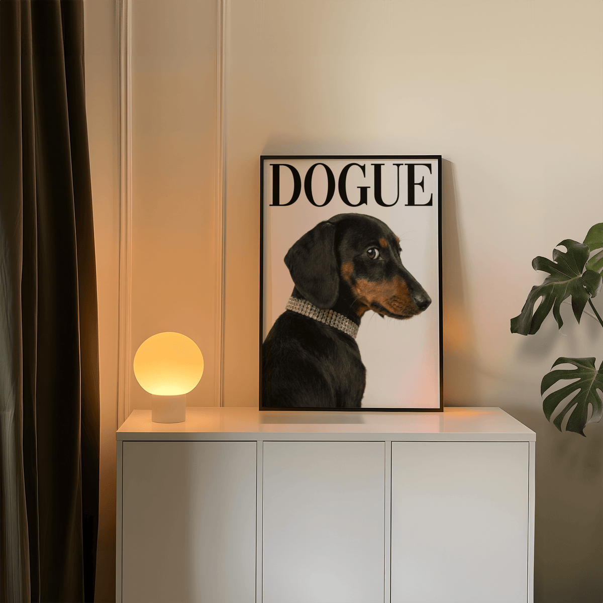 Dachshund art print leaning on a white cabinet next to a round lamp and a plant