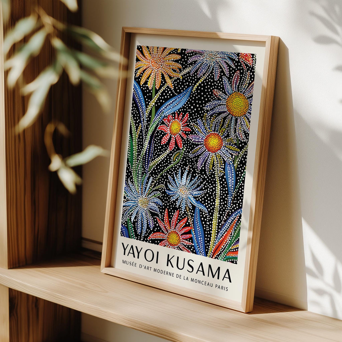 Floral Pop Art framed print of daisies with dot pattern in bright colours leaning on a wooden shelf with blurred leaves