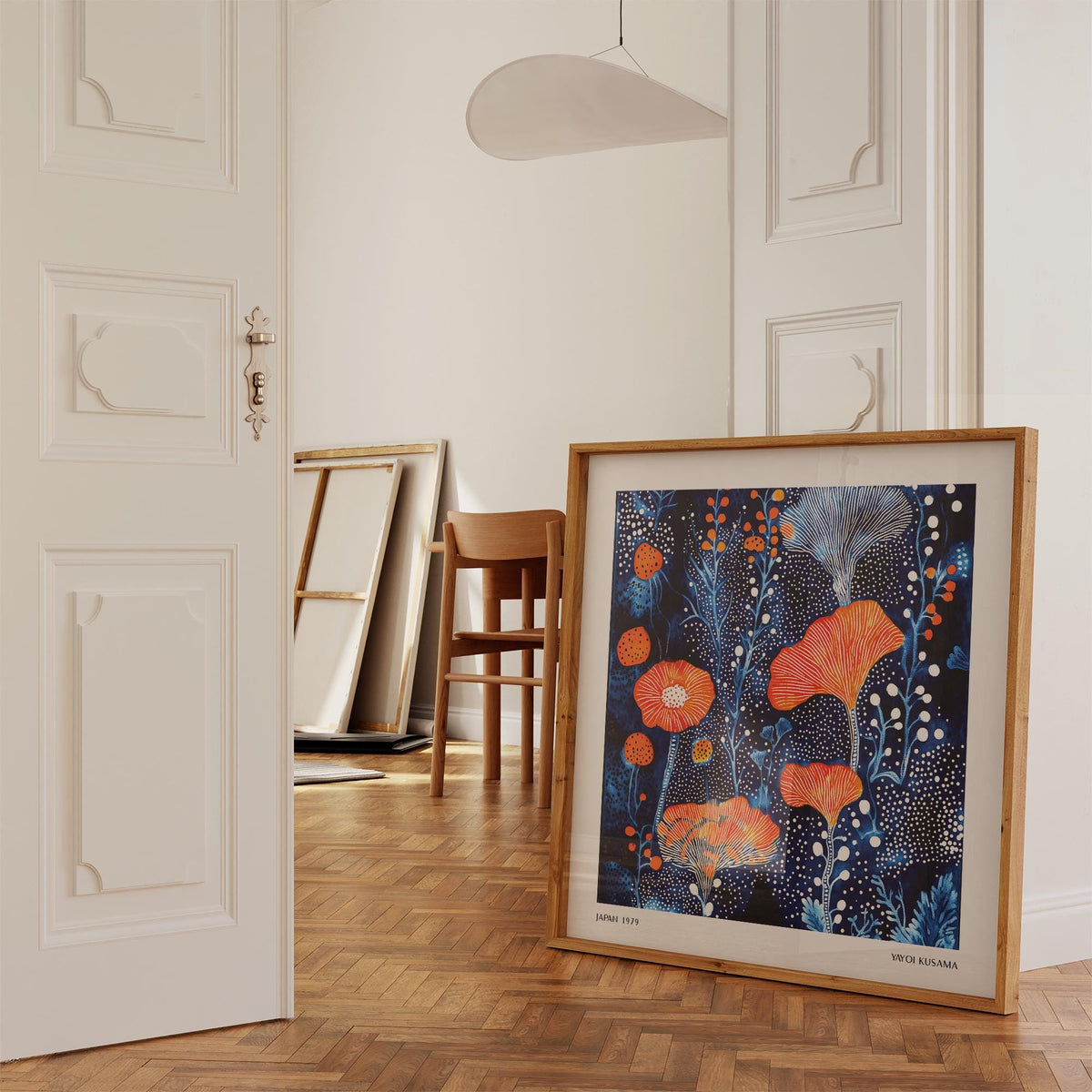 Abstract flower art with coral dots pattern leaning on wooden parquet floor near chair in light room