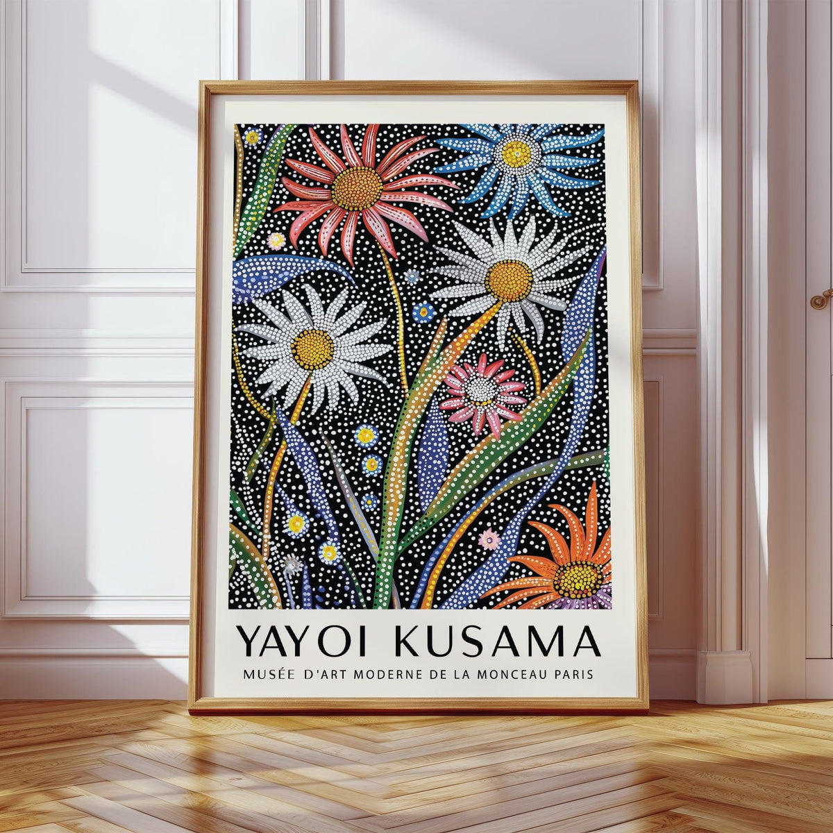 Abstract Botanical wall art with dotted colourful flowers framed and leaning on wooden floorboards by white wall