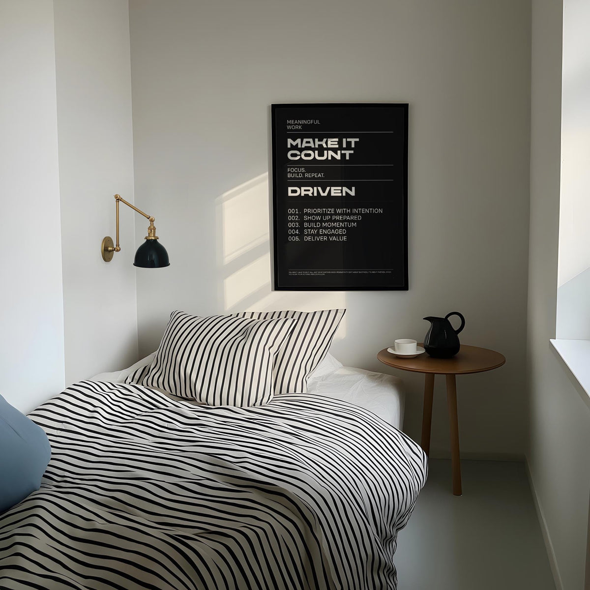 Mindset wall art motivational text poster in black and white above a bed with striped bedding and a side table with a jug