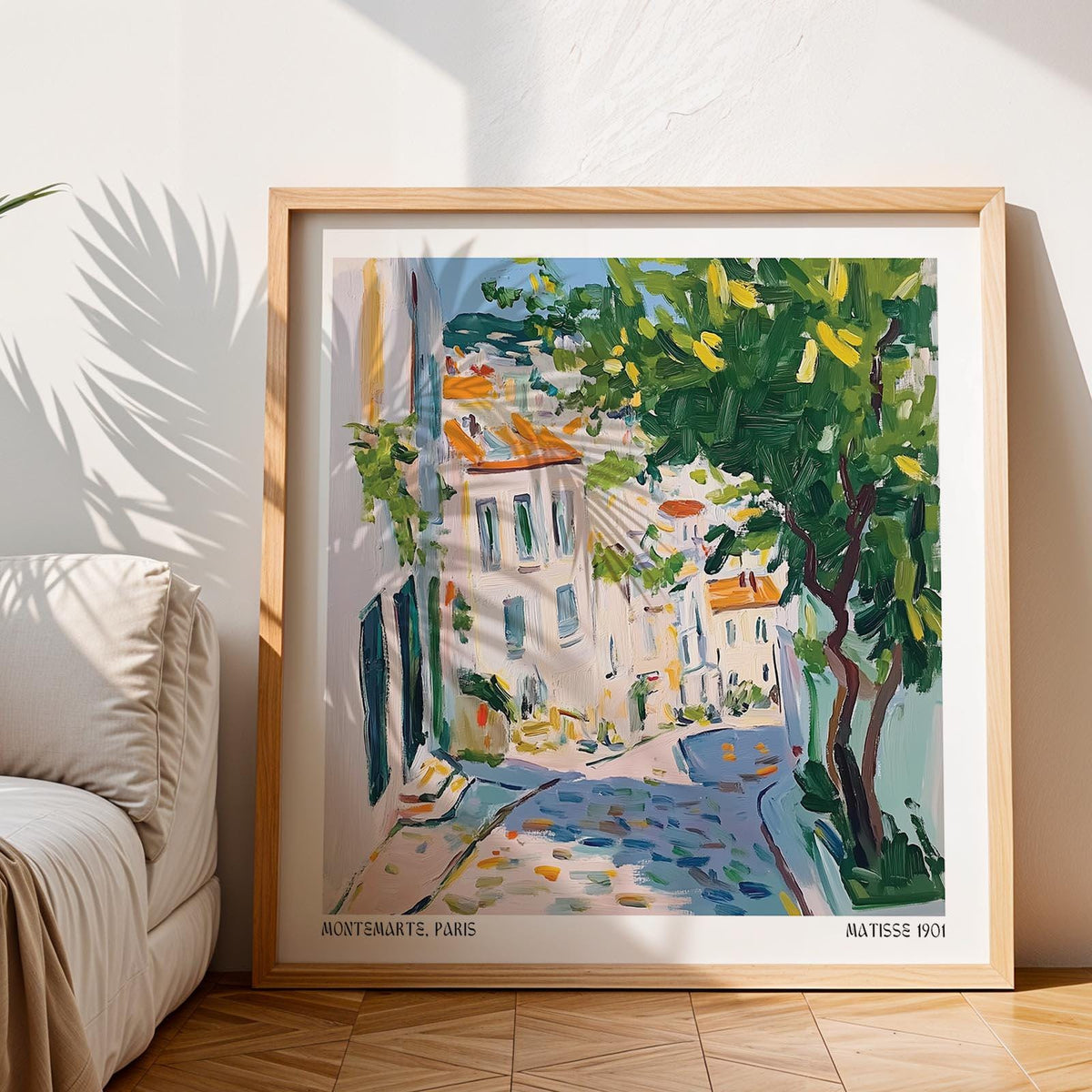 Framed French artwork prints of a Paris street with green tree and blue sky near a sofa
