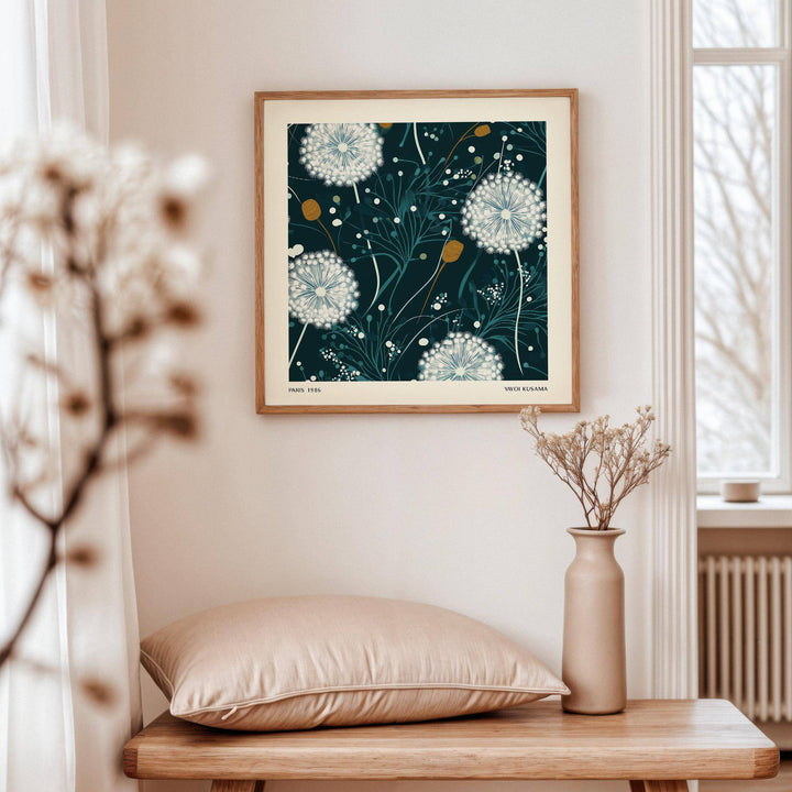 Dandelion wall art of white seed heads on dark background above a wooden bench with cushion and vase