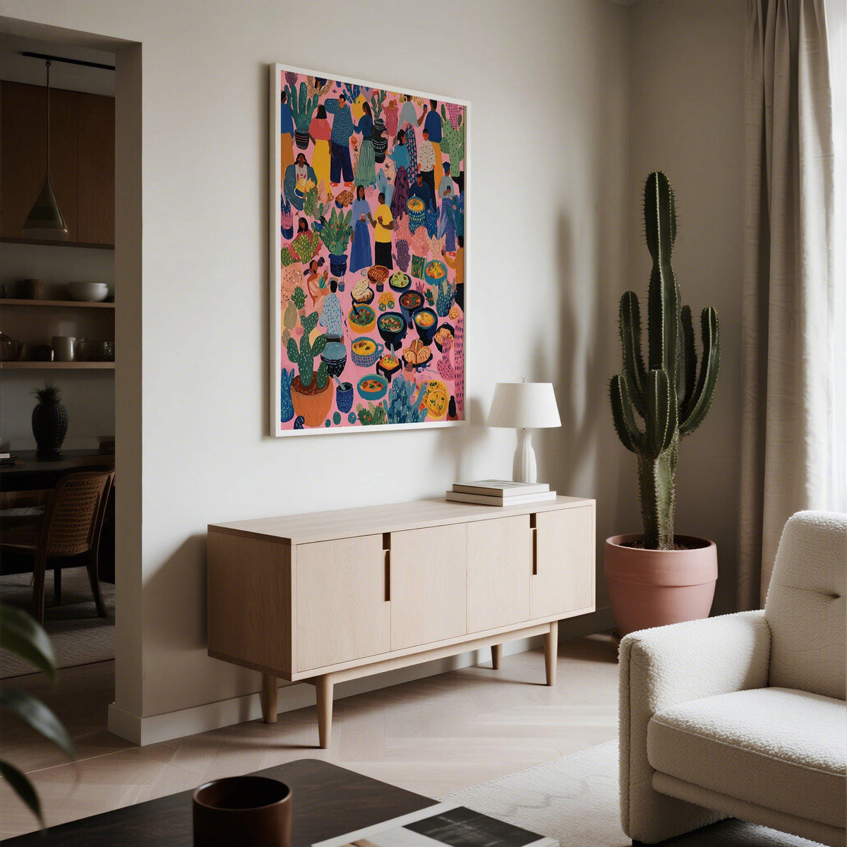 Artwork from Mexico showing a colourful market day scene with potted plants and dishes in a neutral living room with a cactus