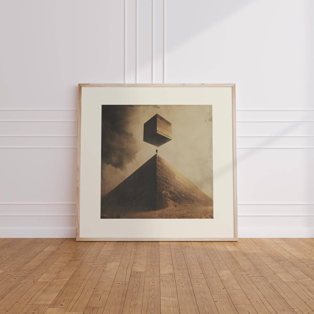 Surreal Pyramid print with floating cube in neutral tones leaning on a wooden floor against a white wall