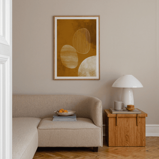 Minimalist line art poster with organic shapes in ochre and beige above a beige sofa and wooden side table in a living room