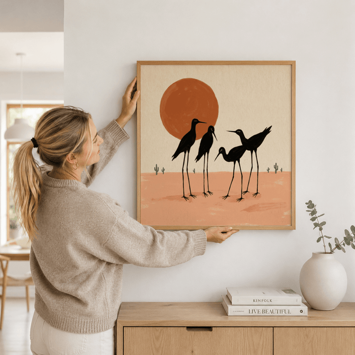 Desert Birds wall art held on a white wall with a console and vase nearby showing silhouetted shorebirds in black and terracotta