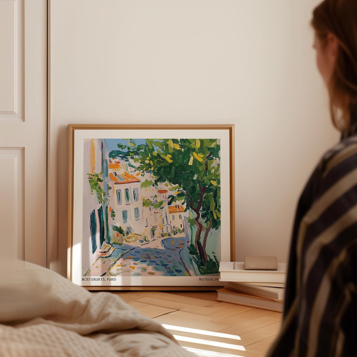 French artwork prints showing a Paris street with a tree leaning on wooden floor beside books