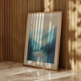 Framed Nature Print of pine trees and mountains in blue and grey hues leaning against a wooden wall