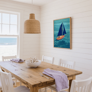 Colorful Sailboart Poster print on a wall in a light dining room with a wooden table and wicker light shade