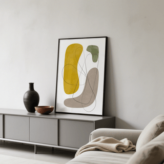 Modern Abstract Wall Art print with yellow green and beige organic shapes leaning on a grey cabinet next to black and brown vases