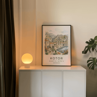 Kotor Landscape Art Print leaning on a white cabinet with a glowing lamp in a neutral room