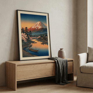 Print leaning on a wooden sideboard of Mount Fuji sunset poster with pink cherry blossoms and boats and a grey decor vase