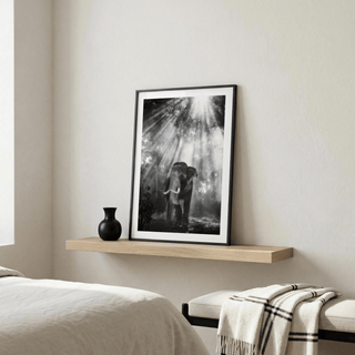 Nature Photography wall art of an elephant in a forest with sunlight beams leaning on a wooden shelf above a bed