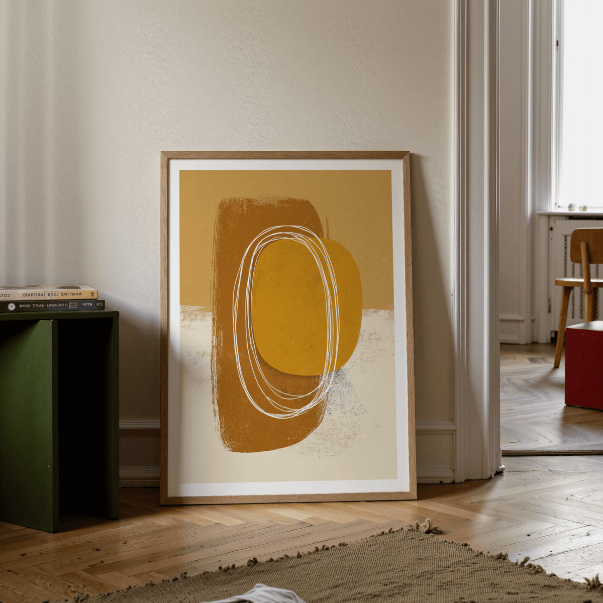 Print leaning on floor of minimalist organic wall art with brown and ochre shapes and white brushstrokes alongside green side table
