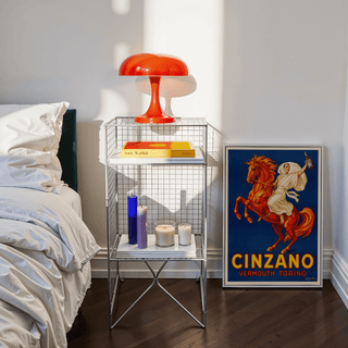 Vintage Italian Aperitif Poster leaning on floor showing man on rearing red horse with bright blue background near bedside table